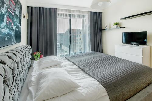 a bedroom with a large bed with a large window at Angel City Center Krakow Aparthotel in Krakow