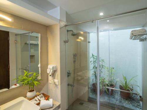 a bathroom with a glass shower and a sink at Ragamaya Resort & Spa Munnar in Munnar