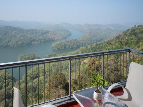 a table and chairs on a balcony with a view of a lake at Ragamaya Resort & Spa Munnar in Munnar
