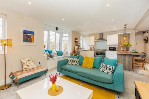 a living room with a blue couch and a kitchen at Exquisite 1BR in Chiswick, 3 min to Train Station in London