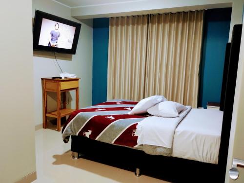 1 dormitorio con 1 cama y TV de pantalla plana en HOSTAL TOSCANO SUITES, en El Tambo