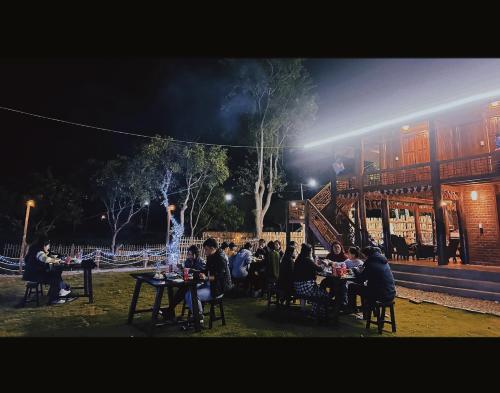 a group of people sitting at tables in front of a building at Homestay Cánh Đồng - Lều Camping & Coffee in Mộc Châu