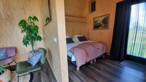 Un dormitorio con una cama y una planta. en Tiny house De Ljip en Westergeest