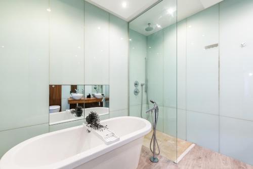 uma casa de banho com banheira e paredes de vidro em Luxury 2 Bedroom Flat in Bell Street em Londres