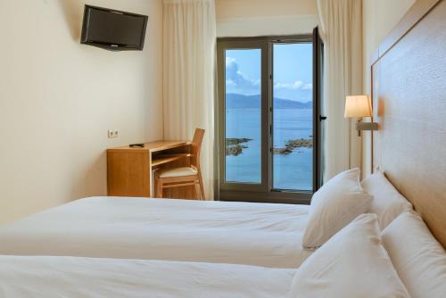 a bedroom with a bed and a desk with a window at Hotel El Puente in Sanxenxo