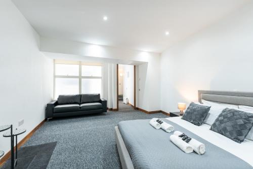 um quarto com uma cama grande e um sofá preto em Luxury 2 Bedroom Flat in Bell Street em Londres