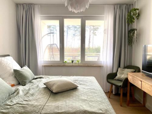 ein Schlafzimmer mit einem Bett, einem Fenster und einem Stuhl in der Unterkunft Ferienwohnung Dünensegler in Juliusruh
