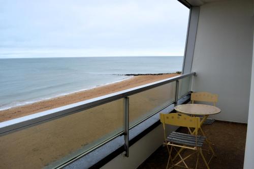 a balcony with a table and chairs looking out at the beach at L'Esperluette - magnifique vue mer et balcon in Courseulles-sur-Mer