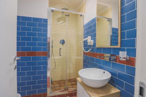 y baño de azulejos azules con lavabo y ducha. en B&B Salerno Centrale, en Salerno