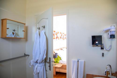 La salle de bains est pourvue de peignoirs blancs suspendus à une porte. dans l'établissement La Bitasyon Tirisyl, à Capesterre