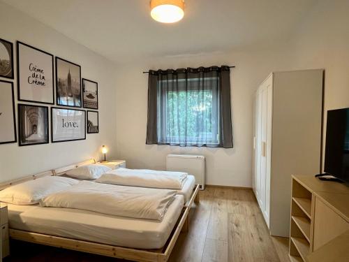 1 dormitorio con 2 camas, TV y ventana en sHome CityHouse Graz - Self-Check-in, en Graz