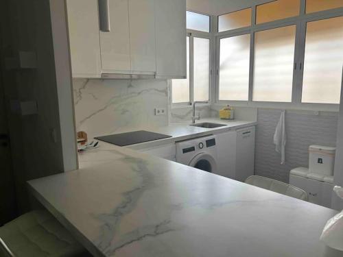 una cucina bianca con piano di lavoro e lavandino di Elegante Loft en San Juan Playa ad Alicante