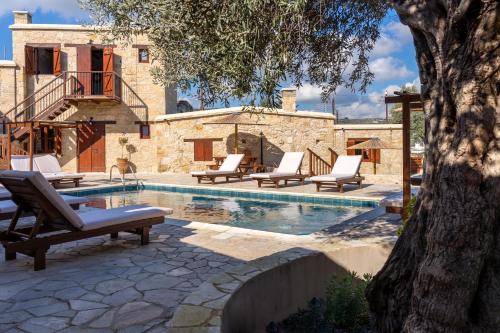a swimming pool with lounge chairs next to a house at Stone Court Boutique Studios in Paphos City