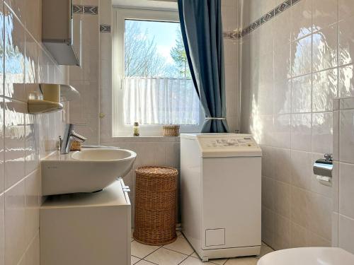 een badkamer met een wastafel, een toilet en een raam bij Urlauberdorf Haus 51a in Boltenhagen