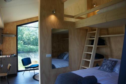 a bedroom with a bunk bed and a mirror at Tiny house De Wylp in Westergeest