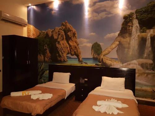 Habitación con 2 camas y una pintura en la pared. en Cairo Paradise Hotel, en El Cairo