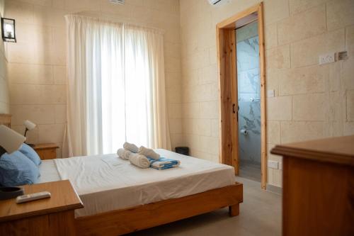 a bedroom with a bed with towels and a window at Ta' Pupa Farmhouse - Sannat in Sannat