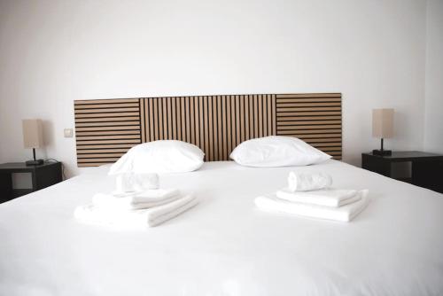1 cama blanca grande con 2 toallas en Cozy 3 bedroom house with 11 kw electric car charger, en Hesperange