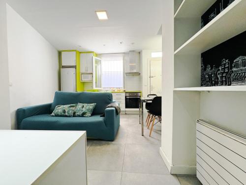 a living room with a blue couch and a kitchen at Luminoso, con patio y buena zona in Madrid