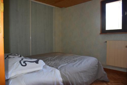Bett in einem Zimmer mit Fenster in der Unterkunft Appartement 2 adultes 2 enfants in La Paute