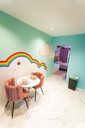 a dining room with a table and chairs and a rainbow on the wall at Capsule cloud - jacuzzi - projecteur cinema in Tourcoing
