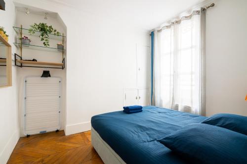 a bedroom with a blue bed and a window at Appartement Quartier Musée du Louvre Free Netflix in Paris