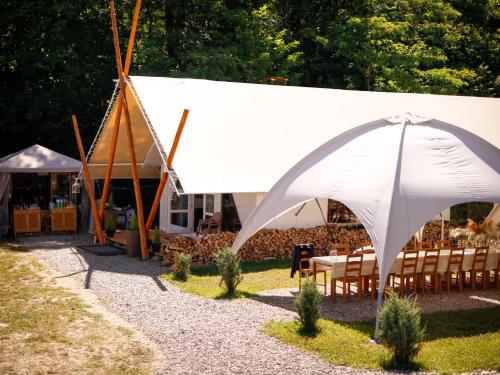 a white tent with chairs and a table in a yard at PINIALE GLAMPING TRIB in Bughea de Jos