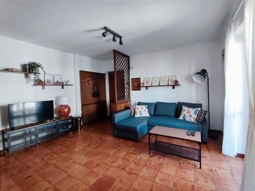 un salon avec un canapé bleu et une télévision dans l'établissement MadreSila Home, à Camigliatello Silano