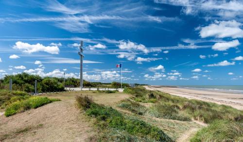 a beach with a flag on a pole and the ocean at L'Esperluette - magnifique vue mer et balcon in Courseulles-sur-Mer