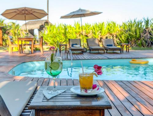 a table with two drinks on a table next to a pool at Aldeia da Mata Ecolodge in Serra Grande