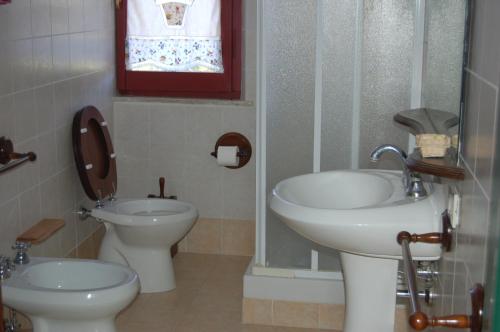 ein Bad mit 2 Waschbecken, einem WC und einem Fenster in der Unterkunft Azienda Agricola Colle Paradiso in Mompeo