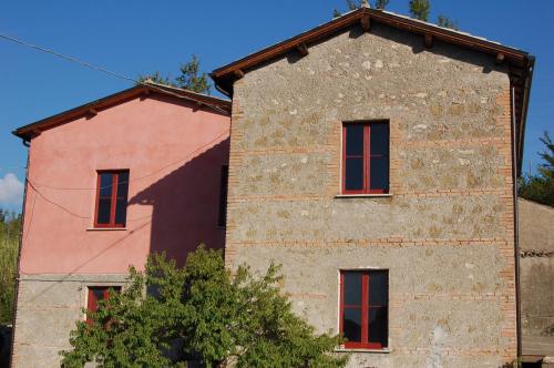 ein altes Backsteingebäude mit roten Fenstern in der Unterkunft Azienda Agricola Colle Paradiso in Mompeo