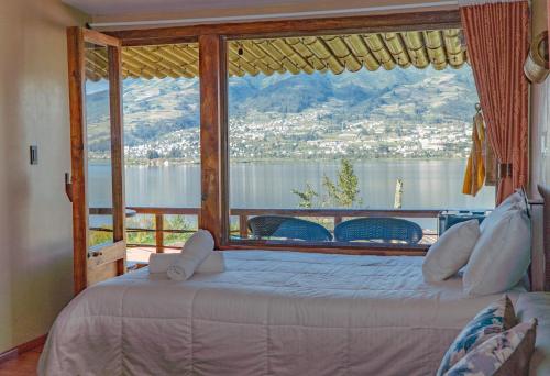 Dormitorio con ventana grande con vistas al agua en Campo Lago Hospedaje, en Otavalo