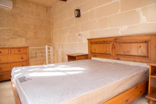 a bedroom with a bed and a brick wall at Ta' Keninu in Sannat