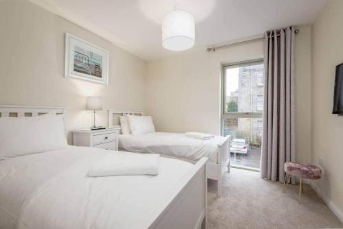 a white bedroom with two beds and a window at Argyle Rigg * Deluxe Central Townhouse * Balcony in St. Andrews