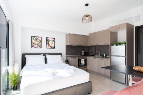 a bedroom with a large white bed and a kitchen at Velvet Luxury Studios in the City Center by BiNoBi! in Thessaloniki