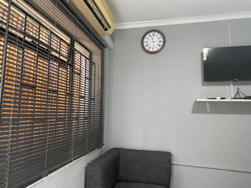 a room with a chair and a clock on the wall at Ashridge Guesthouse & Safaris in Hazyview