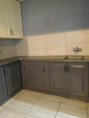 a kitchen with gray cabinets and a sink at Ashridge Guesthouse & Safaris in Hazyview