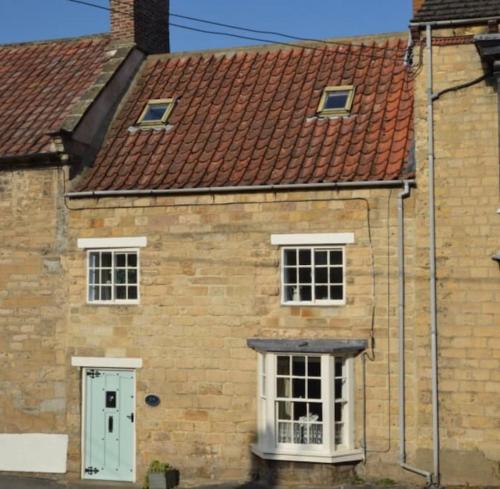 an old brick building with a white door and windows at Castlegate Cottage in Pickering
