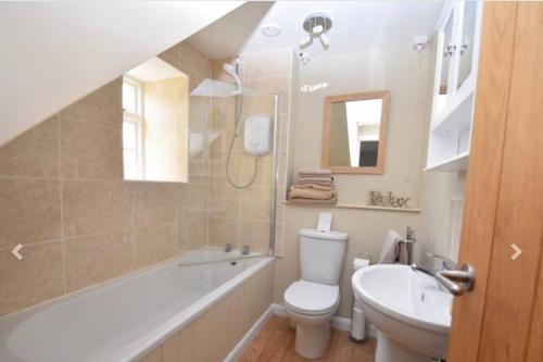 a bathroom with a toilet and a sink and a bath tub at Castlegate Cottage in Pickering