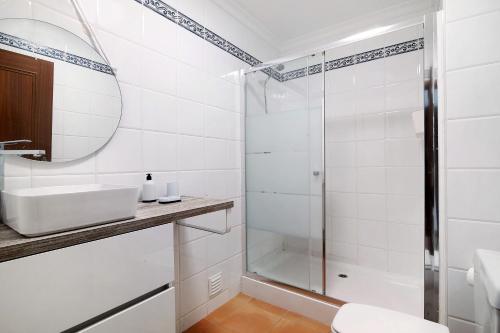 a white bathroom with a shower and a sink at Apartamento Mar a Vista in Portimão