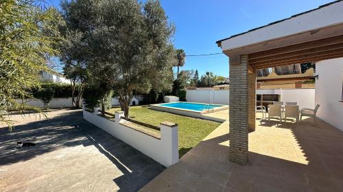 un patio trasero con piscina y una casa en Vivienda Rural Atlántico Sur & Family, en Conil de la Frontera