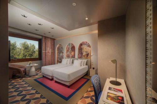a bedroom with a white bed and a large window at NH Collection Roma Vittorio Veneto in Rome