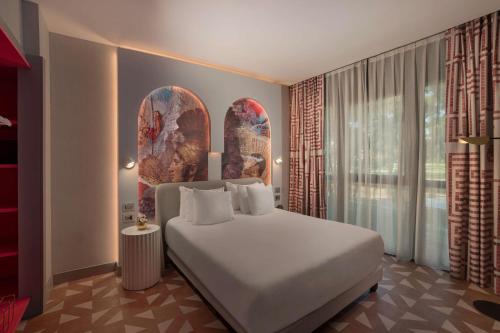 a bedroom with a white bed and a large window at NH Collection Roma Vittorio Veneto in Rome