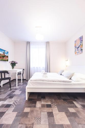 a white bedroom with a bed and a table at Apartmány U zámku in Český Krumlov