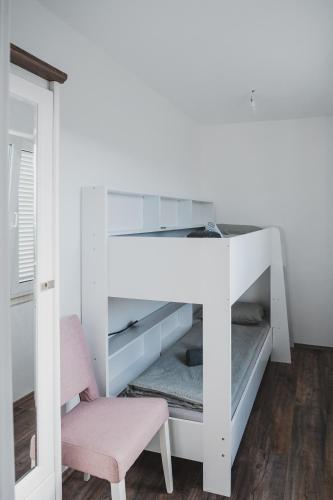 a white bunk bed with a pink chair in a room at Villa Sabrina in Klimno