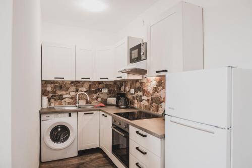 una cucina con mobili bianchi, lavatrice e asciugatrice di Villa Sabrina a Klimno