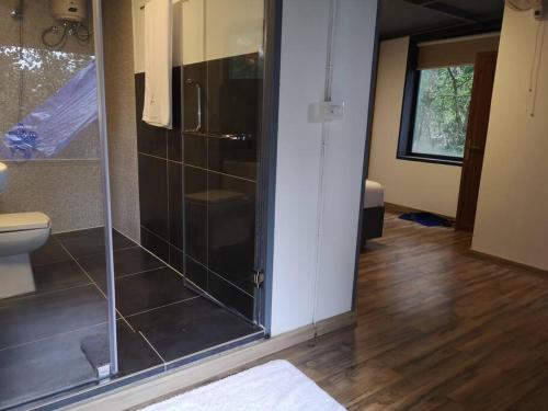 La salle de bains est pourvue d'une douche en verre et de toilettes. dans l'établissement Wildrootstay 3 bed cottage, à Pinangode