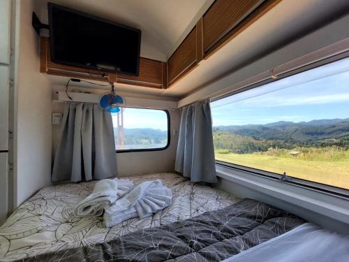 um quarto com uma cama e uma televisão de ecrã plano em Trailer na montanha próximo de Monte Verde em Camanducaia