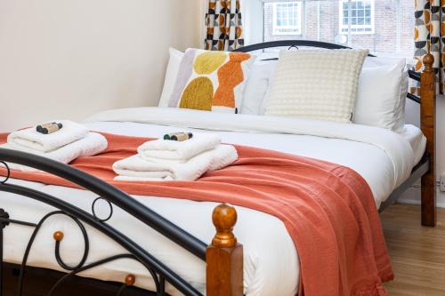 a bed with white and orange blankets and pillows at Peaceful 1BR in Vibrant South Bank, 7min Borough in London